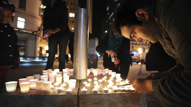 Mario Buda lights candles during a vigil commemorating victims of a Connecticut elementary school shooting in Oakland